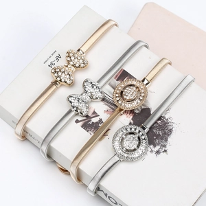 Détail de ceintures élastiques en métal avec nœuds en strass et boucles rondes dorées