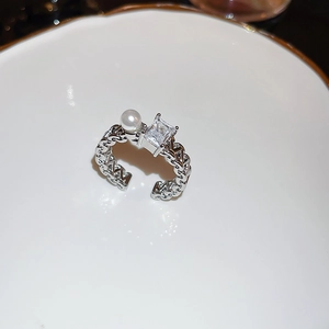 Detail of silver chain ring featuring a white pearl and a square clear zircon