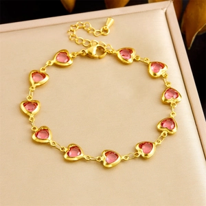 Détail d'un bracelet doré avec dix cristaux de cœur roses facettés sur texture cuir