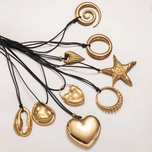 Macro view of gold stainless steel pendants with heart and starfish shapes on black cords