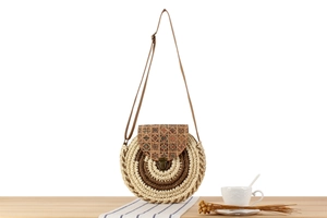 Detailed view of woven round crossbody bag with ethnic print flap on wooden surface