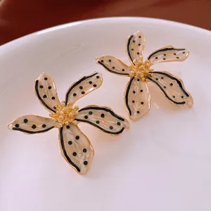 Vintage floral stud earrings with black polka dots and gold accents on a ceramic dish