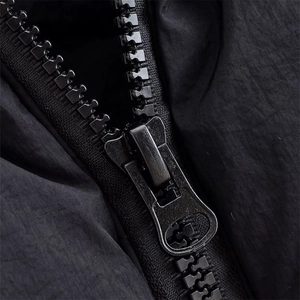 Close-up of matte metal zipper and fine textile texture on a black puffer vest jacket