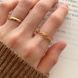 Detail of 925 sterling silver chain ring and minimalist gold band worn on hand