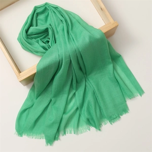 Detail of green cotton linen scarf texture featuring elegant frayed fringe edges