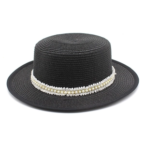 Detail of black straw boater hat featuring pleated white lace and elegant pearl trim