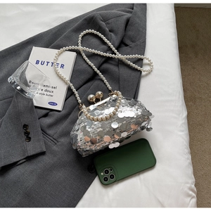 Detail of silver sequin bag with kiss-lock closure, pearl strap, and stylish accessories