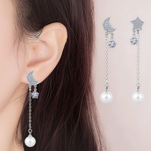 Detail of star and moon silver earrings with blue zircon stones and pearl tassels