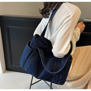 Deep blue denim tote bag with side pocket shown on a model for size perspective