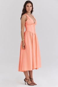 Detail of the deep V-neckline and pleated hem on an orange-pink midi dress with sleek fabric