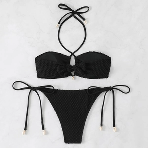 Detail of black textured bikini set with decorative white shells on marble background