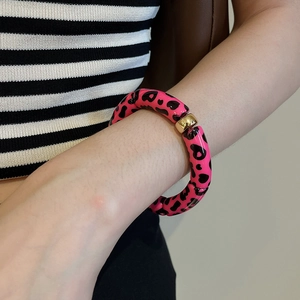 Macro view of leopard print resin beads with a gold sphere connector on a woman's wrist