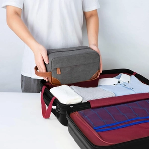 Vintage canvas and PU leather men's toiletry bag being packed into a travel suitcase.
