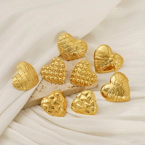 Set of eight gold heart-shaped stud earrings with various textures on stone background