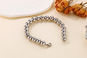 Detailed view of silver titanium steel bead bracelet on a white tray with dried flowers