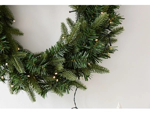 Close-up of green artificial pine wreath with integrated warm white LED string lights