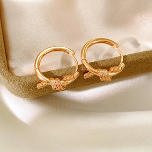 Detail of 18k gold plated knotted hoop earrings with white zircons on velvet box
