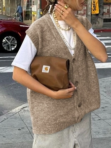 Dettaglio del gilet in maglia marrone con scollo a V e bottoni in uno stile urbano