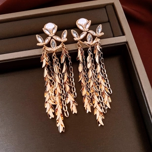 Close-up of 18K gold-plated earrings with pearl flowers and long leaf tassel detail