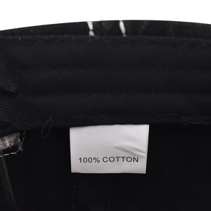 Detail view of the 100% cotton wash label and internal stitching of the black baseball cap