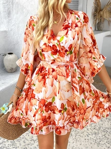 Detail of white wrap dress with orange floral print and waist tie on a Mediterranean background