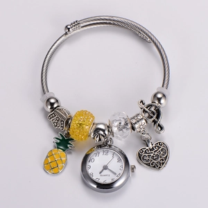 Detail view of silver quartz watch bracelet featuring yellow pineapple and heart charms