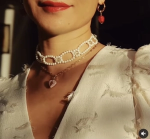 Detail of pink heart pendant and white pearl choker necklace worn with matching earrings
