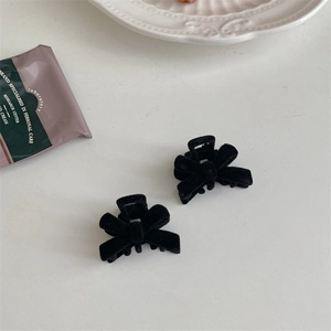 Close-up of black velvet bow hair clips on a white background with decorative porcelain plate