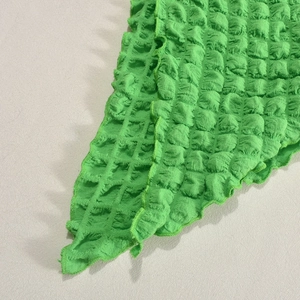 Macro detail of high-stretch green bubble fabric texture with delicate ruffled hem edges
