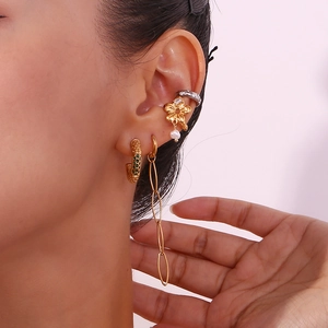 Gros plan de boucles d'oreilles dorées avec strass et perles portées par un mannequin