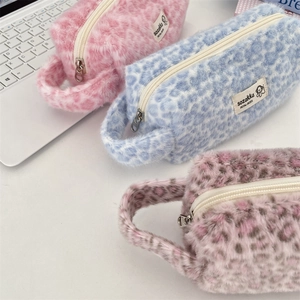 Close-up of three plush leopard print cosmetic bags in pink and blue with zippers