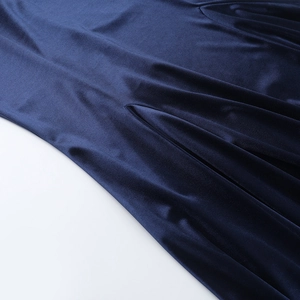 Détail de la texture en velours bleu profond et du drapé de cette robe de soirée élégante