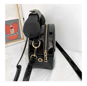 Side view of black patent leather novelty telephone bag with gold zipper and strap hooks