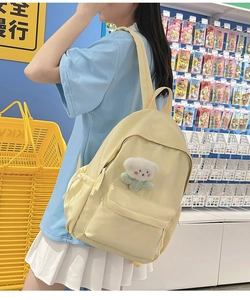Detail of light yellow nylon school backpack with a cute white cloud plush pendant