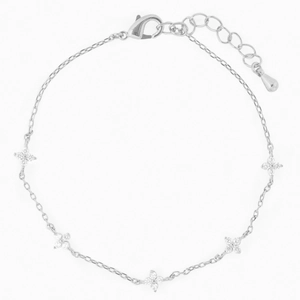 Macro shot of silver four-leaf flower charms with clear crystals on an adjustable bracelet