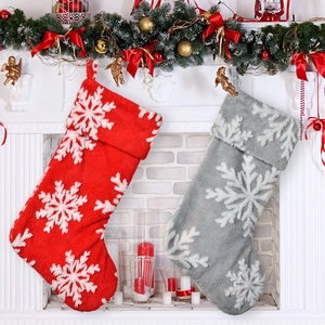 Detail of red and grey plush Christmas stockings with snowflake patterns on fireplace
