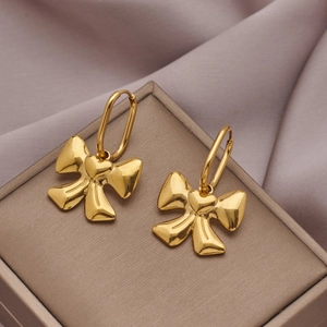 Detail of golden bow earrings with heart charm on a luxury silk and jewelry display box