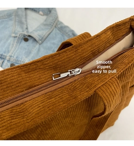 Detail of smooth silver metal zipper on brown corduroy tote bag with textured stripes