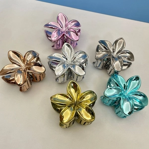 Detailed view of six colorful plumeria flower hair claws with metallic finish texture