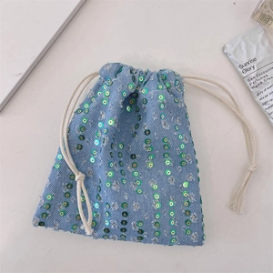 Close-up of light blue denim drawstring bag with green sequins and silver embroidery