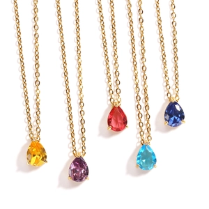 Close-up of five gold necklaces featuring teardrop-shaped gemstones in various colors