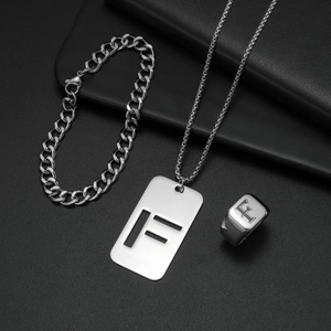 Makroaufnahme von silbernem Edelstahl-Schmuckset mit F-Gravur auf schwarzem Hintergrund