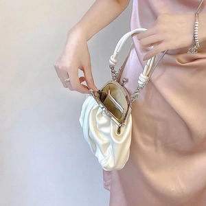 Detail of white pleated satin cloud bag with silver kiss lock and chain strap on model
