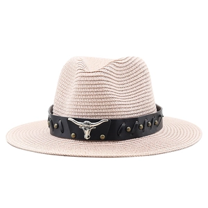 Detail of western straw hat featuring black leather band and silver bull head metal ornament
