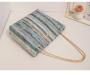 Detail of colorful woven chain bag with rainbow stripes and gold metal strap