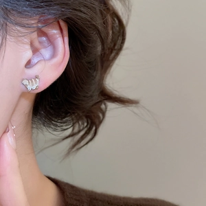 Close-up of cute silver cat stud earring with brown stripes on a model's earlobe