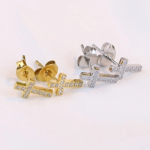 Detailed macro view of cross stud earrings in gold and silver with inlaid cubic zirconia
