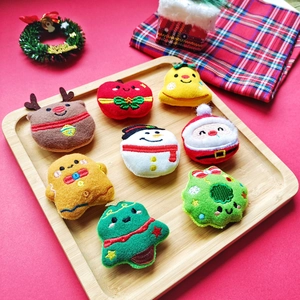Eight Christmas plush pins including reindeer and snowman on a wooden tray with red background