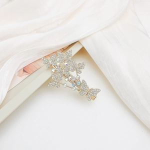 Close-up of golden butterfly hair clip with sparkling rhinestones on white silk fabric