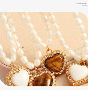 Dettaglio dei ciondoli a cuore su collana di perle eleganti con montatura in oro e zirconi